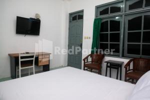 a bedroom with a bed and a desk and a tv at Camila Living Yogyakarta RedPartner in Timuran