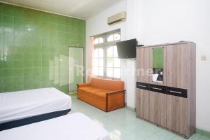 Cette chambre comprend 2 lits et une chaise. dans l'établissement Camila Living Yogyakarta RedPartner, à Timuran