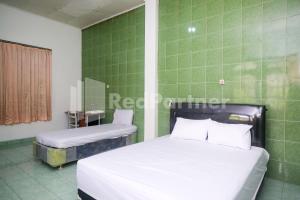 two beds in a room with green tiles at Camila Living Yogyakarta RedPartner in Timuran