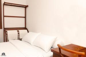 Cama blanca con almohadas blancas y mesa de madera en Pearl Lodge, en Polonnaruwa