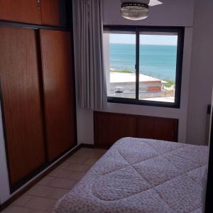 a bedroom with a bed and a large window at Mirador Azul Apart, 3 A,B,C in Las Grutas