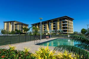 a building with a swimming pool in front of a building at Serenity Zealandia - Luxury 1brm unit at Darwin Waterfront in Darwin
