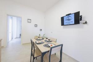 comedor con mesa y TV en la pared en Salentin Home - SeaRelax, en San Pietro in Bevagna