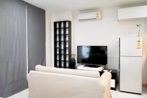 5 mins to BTS Ekkamai, One Bed Fully-Furnished في بانكوك: غرفة معيشة مع أريكة بيضاء وتلفزيون