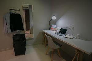 een kamer met een bureau met een laptop en een stoel bij Bluewaters Collab Quarters in Singapore