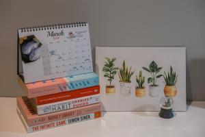 una pila de libros y un calendario y plantas en macetas en Bluewaters Collab Quarters, en Singapur