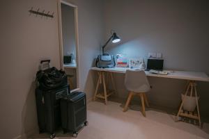 Zimmer mit einem Schreibtisch mit einer Tasche und einem Koffer in der Unterkunft Bluewaters Collab Quarters in Singapur