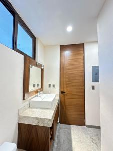 baño con lavabo y puerta de madera en Hermoso Departamento en Tulum en Tulum
