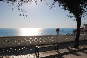 a bench sitting next to a white fence with the ocean at Affittacamere dei Desideri in Numana