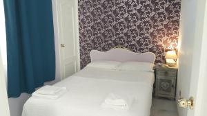 1 dormitorio con cama blanca y papel pintado con motivos florales en Del Parque Flats Calle Nueva Quiet, en Málaga