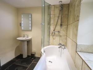 een badkamer met een bad en een wastafel bij Scales Cottage in Lorton