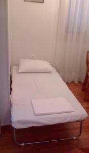 a small bed in a room with white sheets at Manousi 1- Ground floor in Mystras