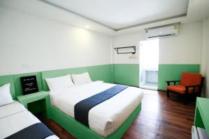 Habitación verde y blanca con cama y silla en The Ram Hotel, en Min Buri