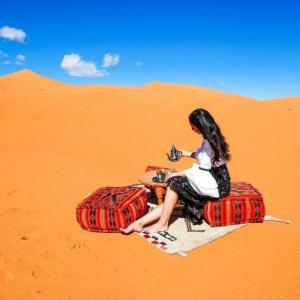 a woman sitting on a camel in the desert at Holiday Desert Camp in Merzouga