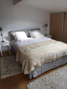 um quarto com uma cama grande com lençóis brancos e almofadas em Chalet de 2 chambres avec terrasse et wifi a Viry em Viry