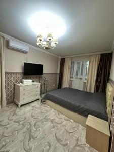 een slaapkamer met een bed, een dressoir en een televisie bij Апартаменты люкс класса in Karagandy
