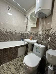 een badkamer met een toilet, een wastafel en een bad bij Апартаменты люкс класса in Karagandy