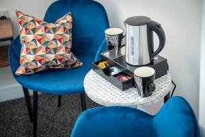 una silla azul y una mesa con una cafetera. en Kings Arms Suites - Deluxe Room - En-Suite - Self Check In, en Whitehaven