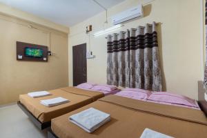a room with three beds and a tv in it at Hotel Ambika in Kolhapur