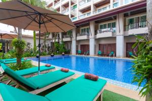 a hotel pool with lounge chairs and an umbrella at Thanthip Beach Resort - SHA Extra Plus in Patong Beach