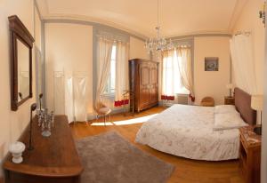 a bedroom with a bed and a table and windows at Château Robert in Raon-lʼÉtape