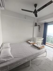 a white bedroom with a bed and a ceiling fan at Dhayra's Seascape Apt @Dapoli in Dapoli