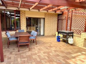 eine Terrasse mit einem Tisch, Stühlen und einem Grill in der Unterkunft Lacey's Holiday House in Kingscote