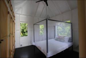 a bedroom with a canopy bed with two windows at Sugar Mountain Cottage in Saint Mary
