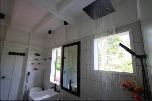 baño con lavabo, espejo y ventana en Sugar Mountain Cottage, en Saint Mary