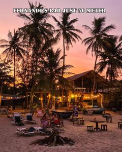 einen Strand mit Stühlen und Palmen bei Sonnenuntergang in der Unterkunft ROLEX GUEST HOUSE in Trincomalee
