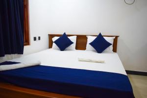 Bett mit blauer und weißer Bettwäsche und blauen Kissen in der Unterkunft ROLEX GUEST HOUSE in Trincomalee