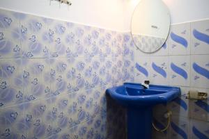 ein Badezimmer mit einem blauen Waschbecken und einem Spiegel in der Unterkunft ROLEX GUEST HOUSE in Trincomalee
