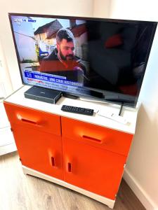 an orange entertainment center with a flat screen tv at ORANGE APPART in Tourcoing