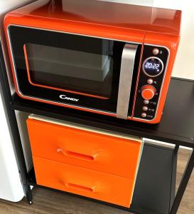 an orange microwave oven sitting on top of a shelf at ORANGE APPART in Tourcoing
