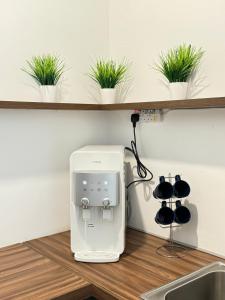 a white appliance on a kitchen counter with plants at SOFEA IMPERIO HOMESTAY @ ALOR SETAR in Alor Setar