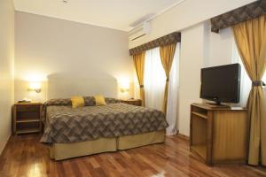 a bedroom with a bed and a flat screen tv at Tritone Hotel in Buenos Aires