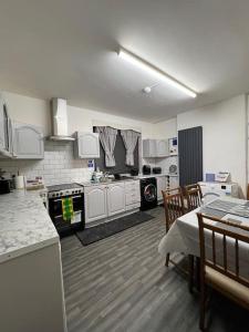 a kitchen with white cabinets and a table and chairs at Newtons Lodge in Nottingham