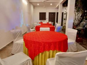 HOTEL SHYAM PALACE INDIA AGRA في آغْرا: غرفة بها طاولة حمراء وكراسي بيضاء
