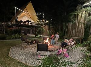a family sitting around a fire in a yard at night at Camp Mai Mee Chue in Pong Yaeng