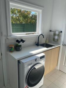 a washing machine in a kitchen with a window at Freshly renovated gem - 1.5km from the city centre in Quarry Hill