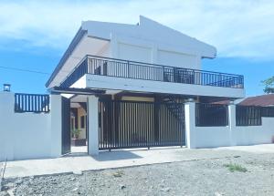 Dieses weiße Haus verfügt über einen Balkon und ein Tor. in der Unterkunft Asanuma General Santos by RedDoorz in General Santos