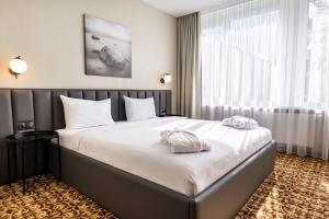 una habitación de hotel con una cama grande con sábanas blancas en Žilvinas Hotel, en Palanga