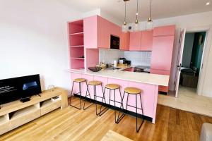 a kitchen with pink cabinets and bar stools at Lilas Rose in Thonon-les-Bains
