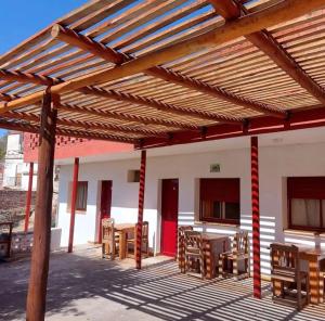 un patio con mesas y sillas bajo una pérgola de madera en Hostería La Porteña - La Serranita en 