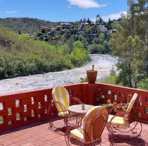 een patio met een tafel en stoelen en een rivier bij Hostería La Porteña - La Serranita in La Bolsa