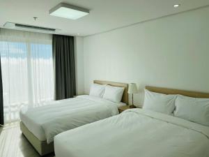 a hotel room with two beds and a window at The Glory Hotel and Residence in Mabalacat
