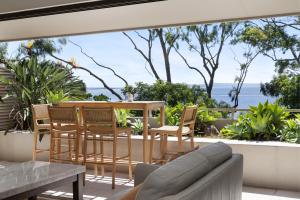 a patio with a table and chairs and a view of the ocean at Cove Point Apartment 5, Little Cove in Noosa Heads