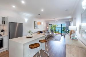 Haven on Hamilton Island -private apartment with views & buggy Fully Renovated in 2023 في جزيرة هاميلتون: مطبخ وغرفة معيشة مع كونتر أبيض