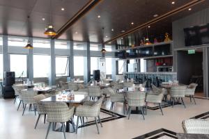 a dining room with tables and chairs and windows at Eno Front One Hotel Semarang in Semarang