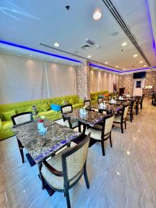 um restaurante com mesas e cadeiras e um sofá verde em Zenith Smart Vacation Homes, Ajman em Ajman